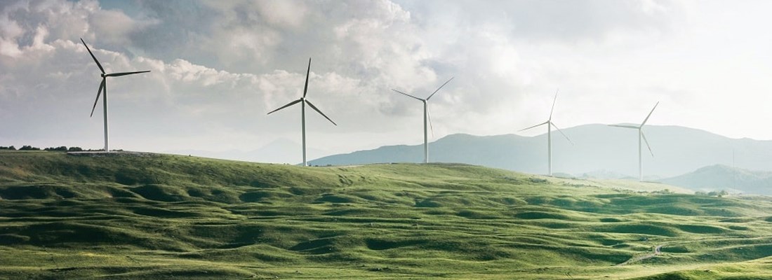 Wind turbines on a green hill.